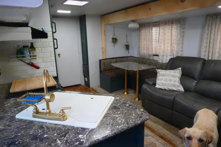 Updated RV rental interior features kitchen, dining booth, comfy living area, and a friendly dog.. Keystone RV Passport Grand Touring 2015