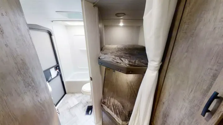Inside this RV rental: compact bathroom with shower, toilet, and comfortable bunk beds.. Forest River Evo 2022