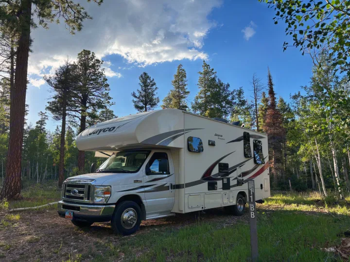 This RV rental is perfectly parked in a sunny forest campsite, surrounded by tall pine and aspen trees for a relaxing outdoors trip.. Jayco Redhawk 2017