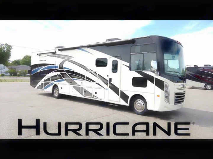 White Hurricane RV motorhome with dynamic graphics, ideal for RV rental. This large recreational vehicle is parked outdoors.. Thor Motor Coach Hurricane 2021