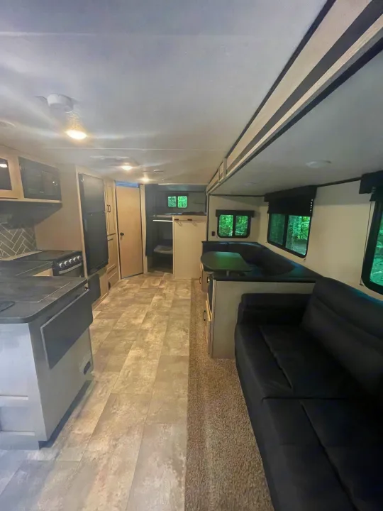 Spacious, comfortable rv rental interior: kitchen, U-shaped dinette, black sofa, and bunk beds, ideal for travel.. Coachmen Other 2022