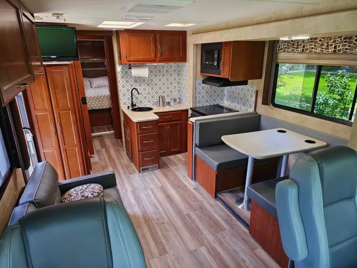 An RV rental interior showcasing a kitchen, dinette, rear bedroom, and front seating area with wood floors.. Thor 29.1 2012
