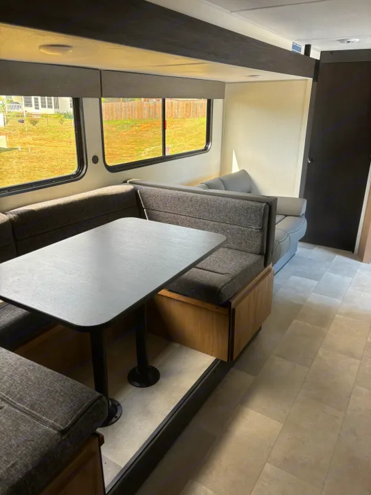 Enjoy this modern RV rental interior featuring a comfy U-shaped dinette, sofa, and large windows.. Forest River Cherokee 26DBH 2024