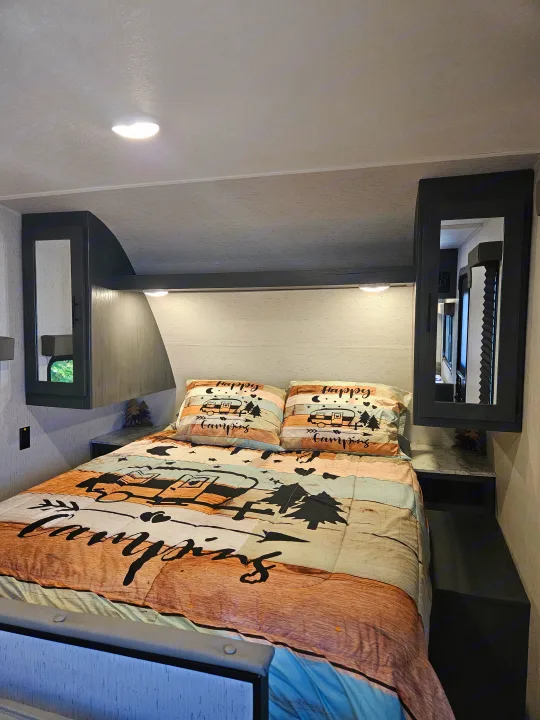 Cozy RV bedroom, perfect for your next rv rental. Features a camping-themed bed, built-in storage, and soft lighting.. Dutchmen TT 2024