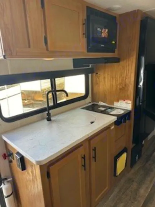This RV rental kitchenette offers a sink, stovetop, microwave, and fridge, perfect for travel & camping adventures.. Sportsmen 181BH 2022