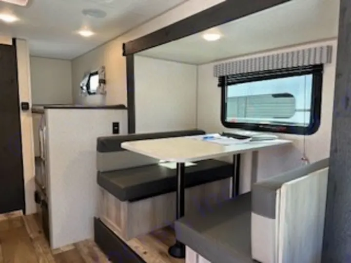 This spacious RV rental interior features a comfortable dinette with bench seats, a window, and a rear sleeping area/bunk beds.. Sportsmen 181BH 2022