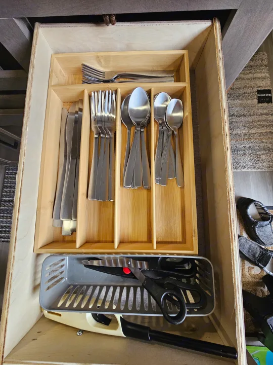 Neatly organized RV rental kitchen drawer: wooden cutlery holder for silverware, plus scissors & lighter storage.. Grand Design Other 2024