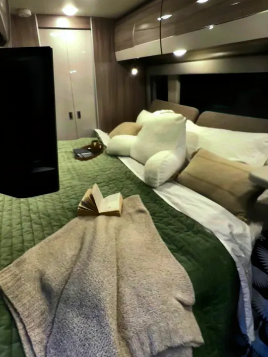 Relax in this cozy RV rental bedroom with a quilted bed, TV, and overhead storage for your journey.. Thor Sequence 2023