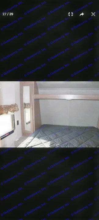 Inside an RV rental: a compact bedroom features a dark bed, window, mirrored closet, and overhead storage.. Keystone RV Hideout LHS 2018