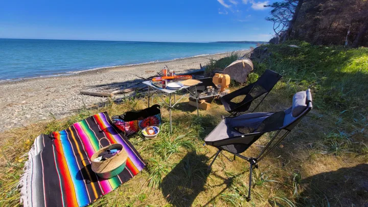 RV rental adventure stop: serene beach camp with portable kitchen, chairs, and colorful blanket by the blue ocean.. MITSUBISHI Delica 1997
