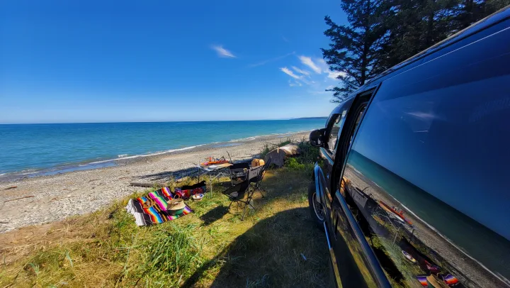 RV rental adventure: a van parked by a scenic blue beach with a vibrant picnic setup and ocean views on a sunny day.. MITSUBISHI Delica 1997