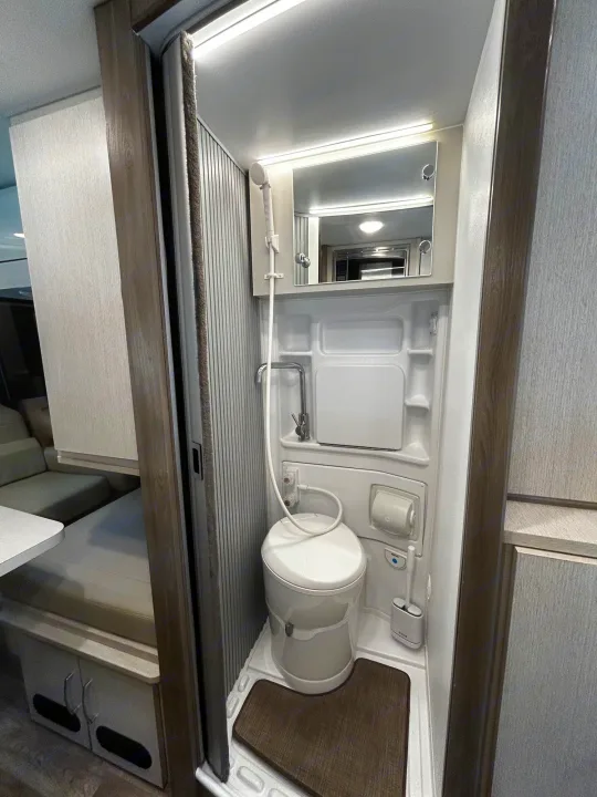 Compact RV rental wet bath featuring a toilet, shower, and sink. This functional space is ideal for travel convenience.. Thor Tellaro 2024