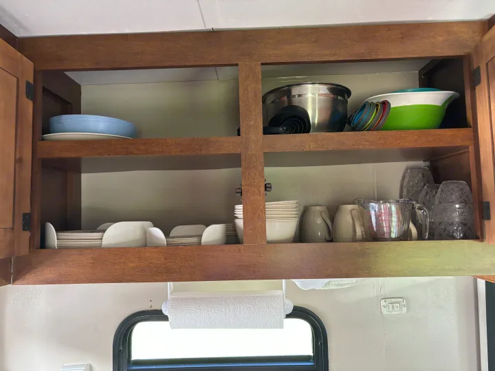 RV rental kitchen cabinet with organized dishes, bowls, mugs, and essential cookware. Ready for adventure meals.. Coachmen Catalina Deluxe Edition 2013