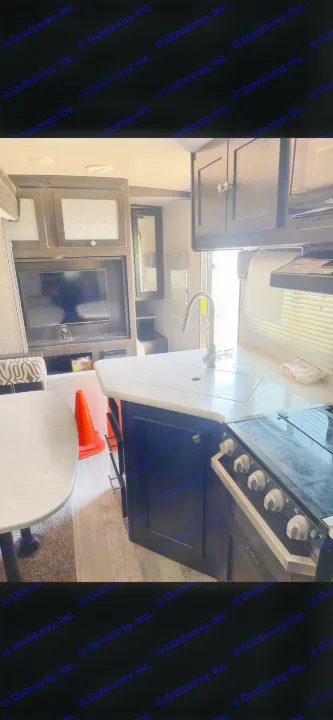 Modern RV rental interior featuring a full kitchen with sink and stove, dining area, and entertainment center.. Heartland RVs North Trail 2019