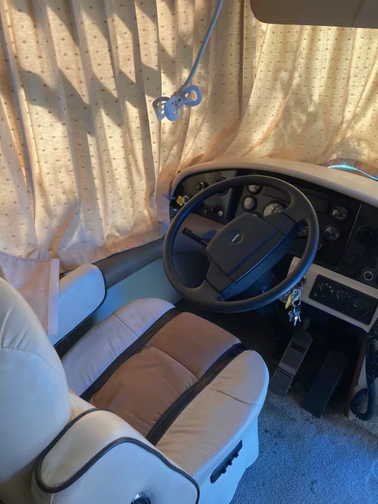 Experience comfort in this RV rental! View of the driver's seat, steering wheel, dashboard, and sunlit patterned curtains.. Fleetwood Expedition 2003
