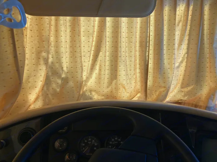 Inside an rv rental: View of the dashboard, steering wheel, and front window curtains with a diamond pattern for privacy.. Fleetwood Expedition 2003