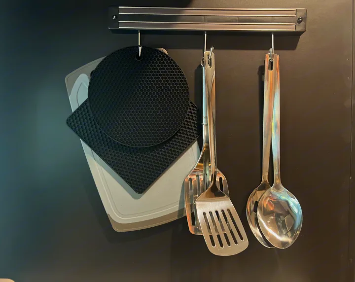 Efficient kitchen storage for your RV rental: spatulas, spoons, hot pads, and a cutting board neatly hung on a magnetic rack.. Keystone RV Springdale 2022