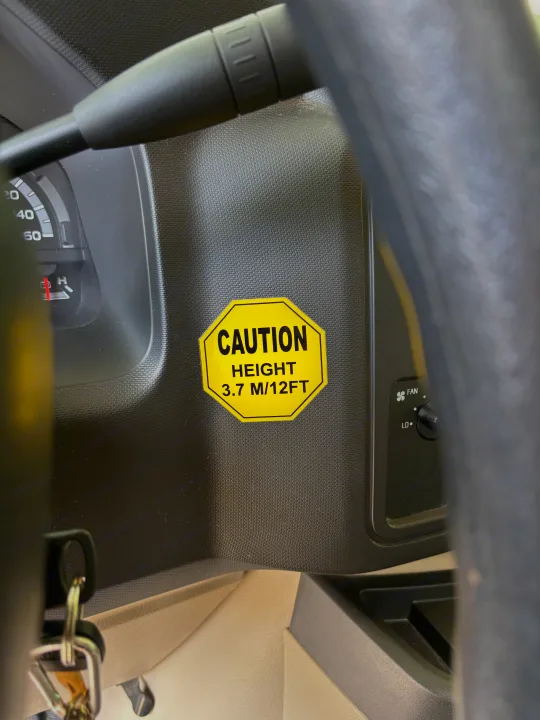 RV rental dashboard with a yellow 'CAUTION HEIGHT 3.7 M/12 FT' sticker, visible for safe driving.. Forest River Sunseeker 2018