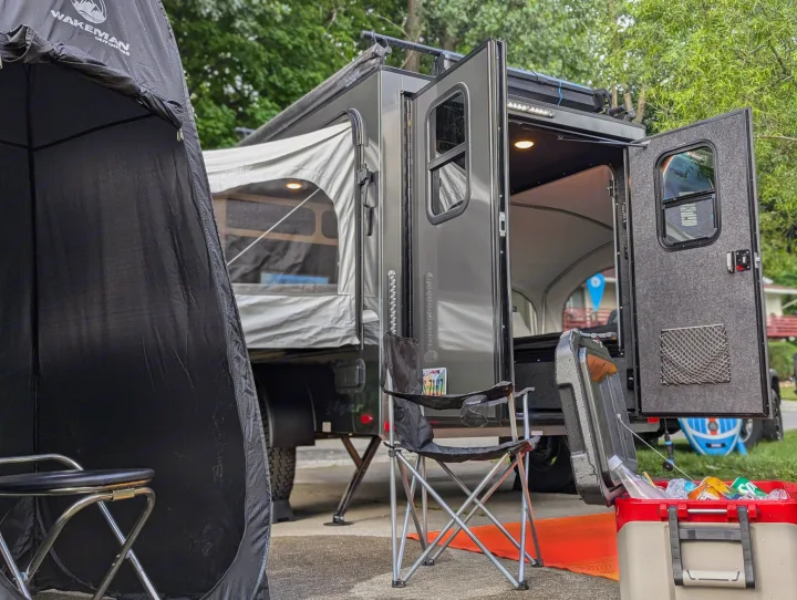 Adventure-ready RV rental setup: dark travel trailer with open doors, a full cooler, & Wakeman tent for outdoor camping.. Intech Flyer Explore 2022