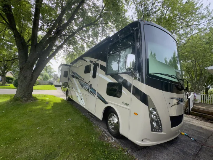 A large, beige and black Thor Windsport RV with an extended slide-out, parked in a driveway, ready for an rv rental.. Thor Windsport 2020