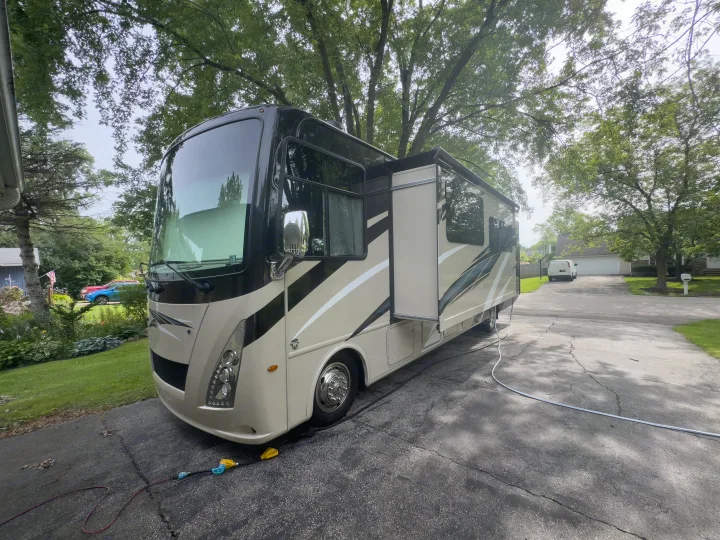 Large beige rv rental with extended slides on a paved driveway, hooked up. Ideal motorhome for family trips.. Thor Windsport 2020