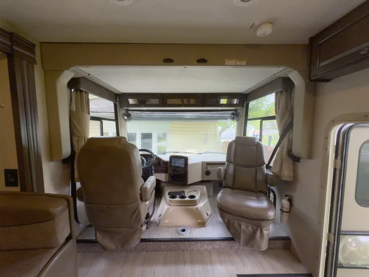 Spacious RV rental interior featuring swivel driver/passenger seats, a detailed dashboard, and overhead storage.. Thor Windsport 2020
