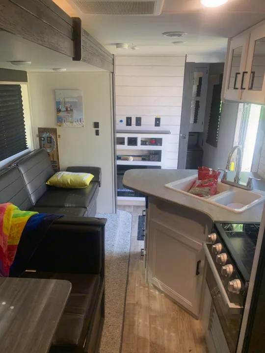 Experience comfort in this RV rental interior, featuring a cozy living area with sofa, dining table, kitchen, and electric fireplace.. Keystone RV Hideout 2023