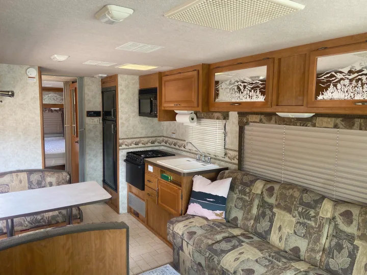 RV rental interior features a full kitchen, dining table, sofa, and etched cabinets. A comfortable mobile living space awaits.. Fleetwood Terra 2003