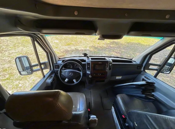 RV rental driver's cabin view: Mercedes-Benz steering wheel, dashboard, and brown leather front seats visible.. Forest River Mercedes 2019