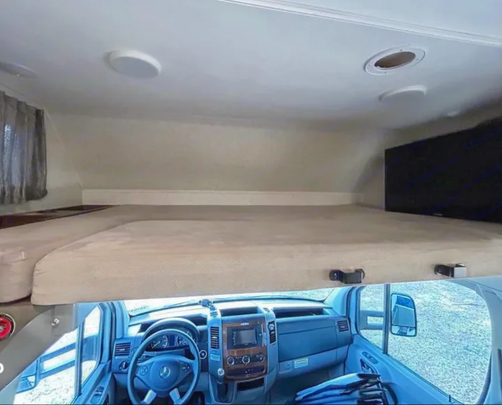 This RV rental's interior shows a comfy cab-over bed, TV, and the driver's cockpit. Explore in comfort!. Forest River Mercedes 2019