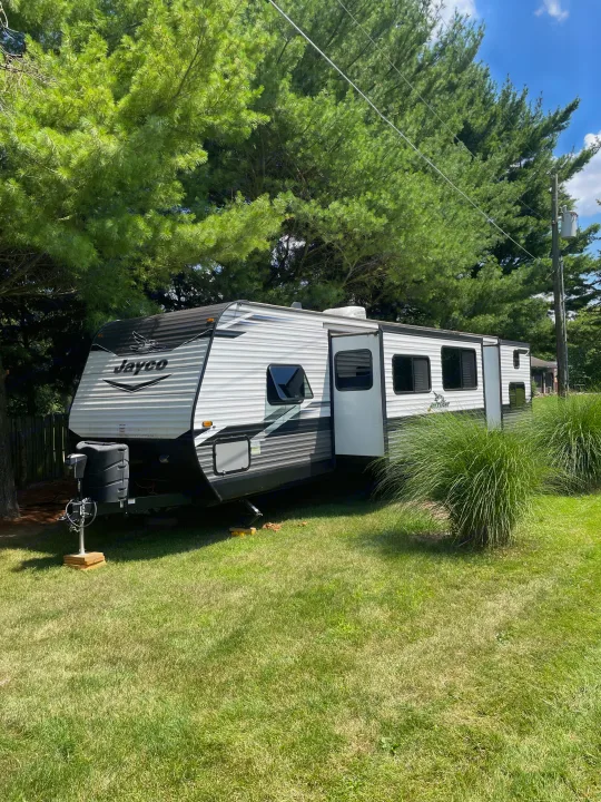 A white and black Jayco RV travel trailer parked on a grassy yard, offering comfortable RV rental stays.. Jayco Jay Flight 2022