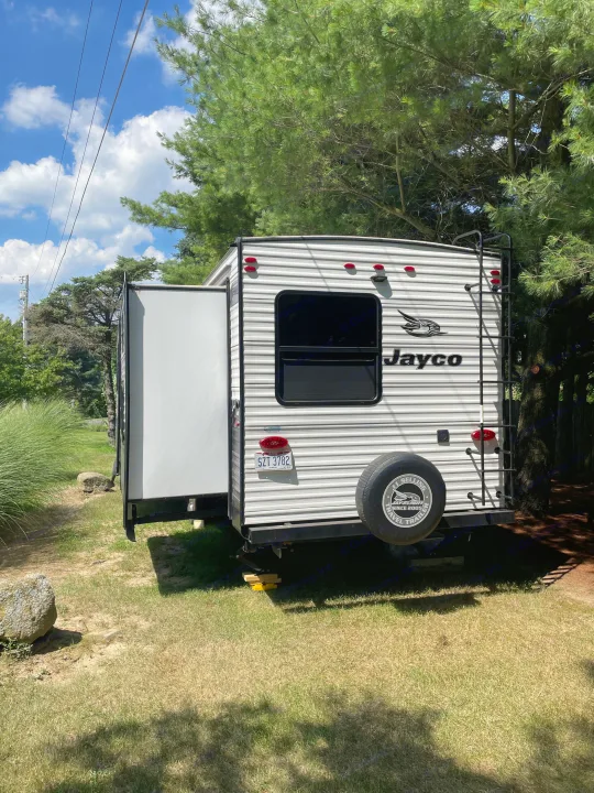 White Jayco rv rental travel trailer with slide-out extended, parked amidst trees. Ohio plate SZT 3782 visible.. Jayco Jay Flight 2022