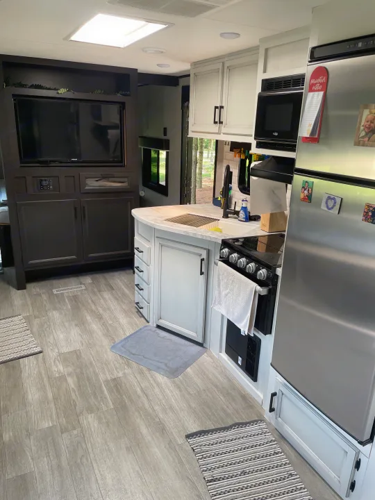 Spacious RV rental interior featuring a modern kitchen with sink, stove, microwave & fridge, plus TV entertainment area.. Jayco Jay Flight 2022