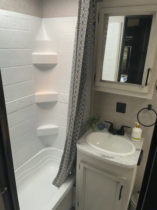 Bright RV rental bathroom with shower/tub, geometric curtain, and vanity with sink.. Jayco Jay Flight 2022