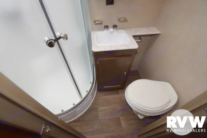 An RV rental bathroom featuring a space-saving corner shower, sink vanity, and toilet.. Forest River Palomino Puma 2018