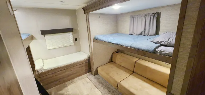 Spacious rv rental interior featuring bunk beds, a sofa, and a padded bench for sleeping.. Aspen Trail Aspen Trail Trailer 2019