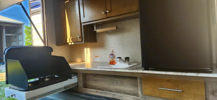 This RV rental's outdoor kitchen offers a slide-out stove, sink with soap, compact fridge, and cabinets. Ideal for camping.. Aspen Trail Aspen Trail Trailer 2019