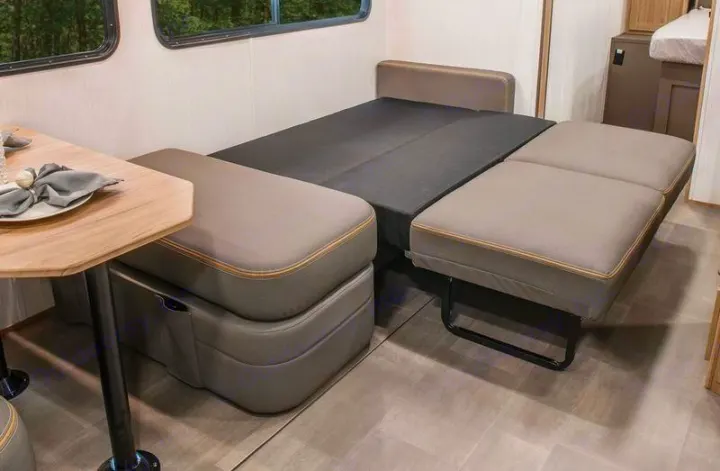 Versatile RV rental interior: A light gray sofa/dinette seamlessly converts into a comfortable bed, optimizing compact living.. Cruiser RV Avenir 2024