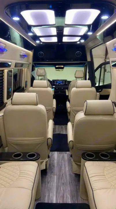 Spacious luxury RV rental interior featuring plush cream captain's chairs, elegant ceiling lights, and modern wood flooring.. Ultimate Toys Ultimate Coach 2022