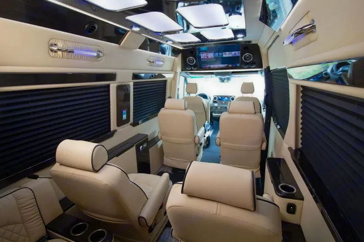 Luxurious RV rental interior with cream leather captain's chairs, entertainment screen, and accent lighting for comfort.. Ultimate Toys Ultimate Coach 2022