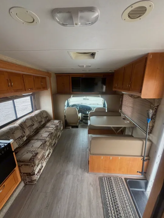 Bright rv rental interior featuring a patterned sofa, dinette, kitchen area, and ample storage. Ideal for comfortable journeys.. Forest River Sunseeker 2009