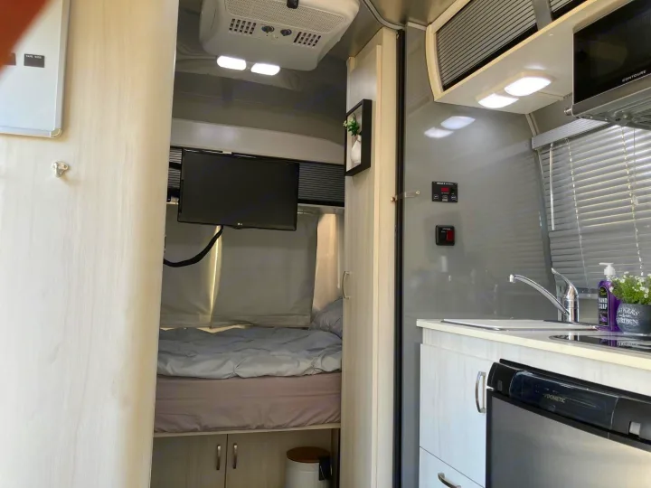 RV rental: well-appointed interior showing bedroom with TV, and kitchen with sink, microwave, Dometic fridge.. Airstream Sport 2017