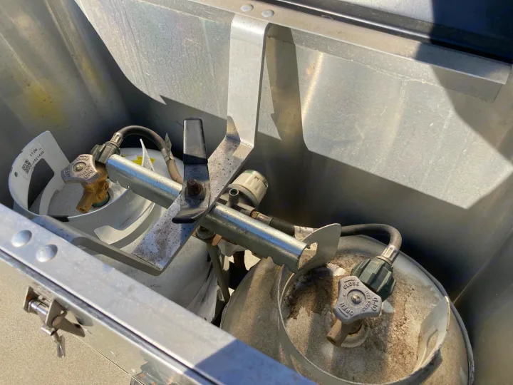 Two propane tanks with a regulator visible in a metal RV rental storage compartment.. Airstream Sport 2017