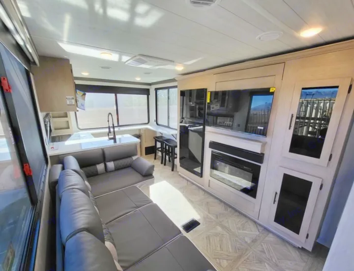Explore this modern RV rental interior: a spacious living area with sectional sofa, full kitchen, and entertainment center.. Forest River Wildwood X-Lite 2024