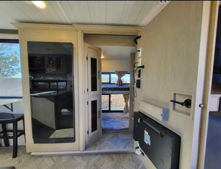 Inside a modern rv rental: kitchen appliances, entertainment wall, and bunk beds. Perfect for family adventures.. Forest River Wildwood X-Lite 2024