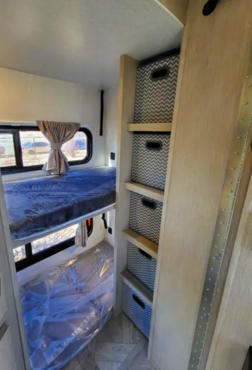 RV rental bunk beds and practical chevron storage unit visible in a well-organized camper interior.. Forest River Wildwood X-Lite 2024