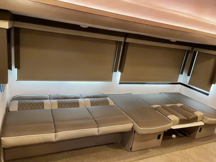 Modern RV rental interior featuring versatile seating/bed, roller blinds, and ambient strip lighting for comfort.. Forest River Wildwood Platinum 2024