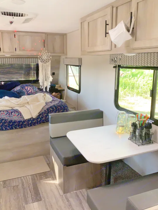 Cozy RV rental interior features an inviting bedroom area, a practical dinette, and bright windows, perfect for adventures.. KZ Sportsmen classic 160QB 2021