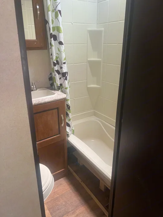 Compact RV rental bathroom with a sink, toilet, and shower-tub combo.. Forest River Wildwood 2018