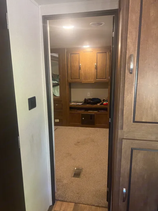 Step inside this cozy RV rental bedroom. Features include wood cabinets, carpeted floor, and bright lighting, perfect for your next adventure.. Forest River Wildwood 2018